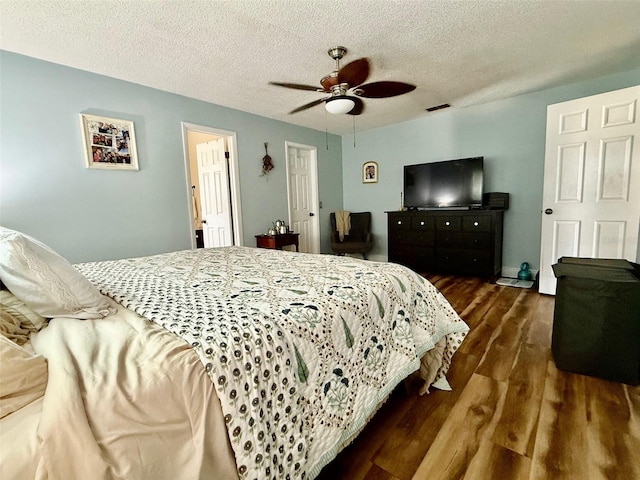 bedroom with dark wood-style floors, ceiling fan, visible vents, and a textured ceiling