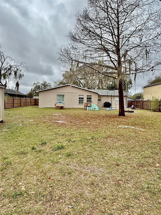 back of property with a fenced backyard and a yard