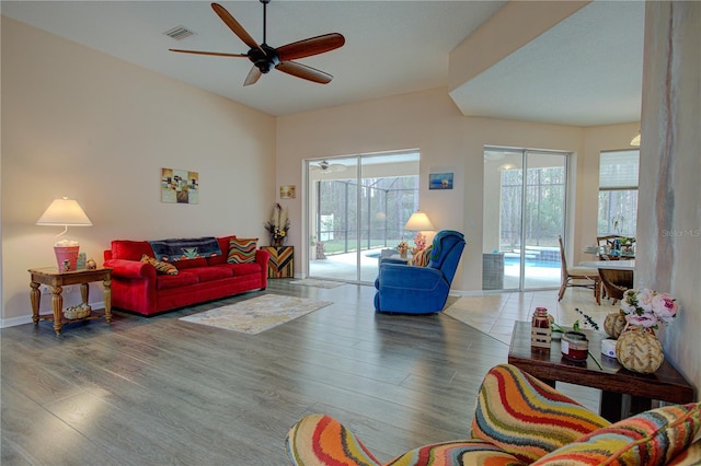 living area with visible vents, ceiling fan, baseboards, and wood finished floors