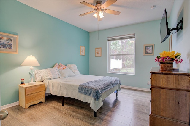 bedroom with light wood-style floors, ceiling fan, and baseboards