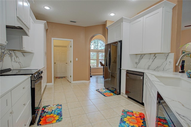 kitchen with light tile patterned floors, a sink, visible vents, white cabinetry, and black appliances