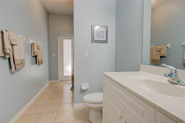 bathroom featuring toilet, vanity, baseboards, and tile patterned floors