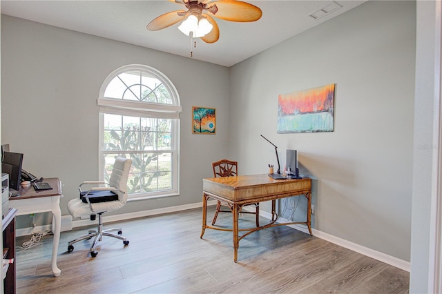 office space featuring a ceiling fan, visible vents, baseboards, and wood finished floors