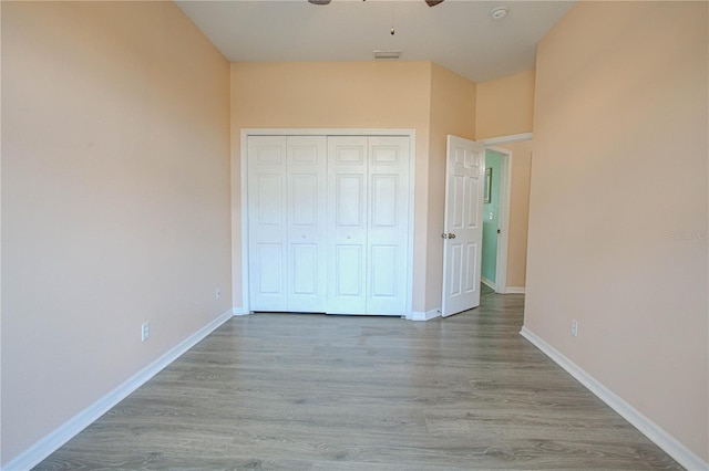 unfurnished bedroom featuring a closet, visible vents, baseboards, and wood finished floors