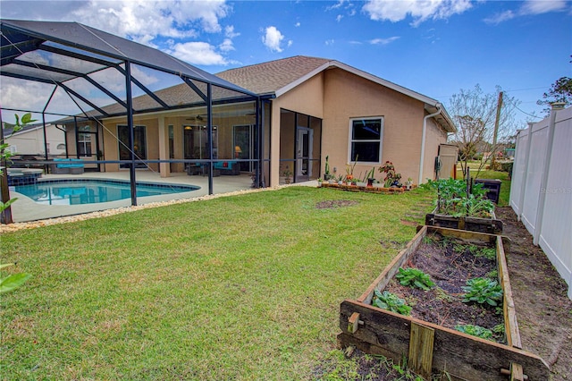 rear view of property with a lanai, a lawn, a vegetable garden, stucco siding, and a patio area