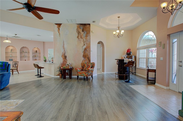 entrance foyer with arched walkways, wood finished floors, visible vents, baseboards, and a tray ceiling