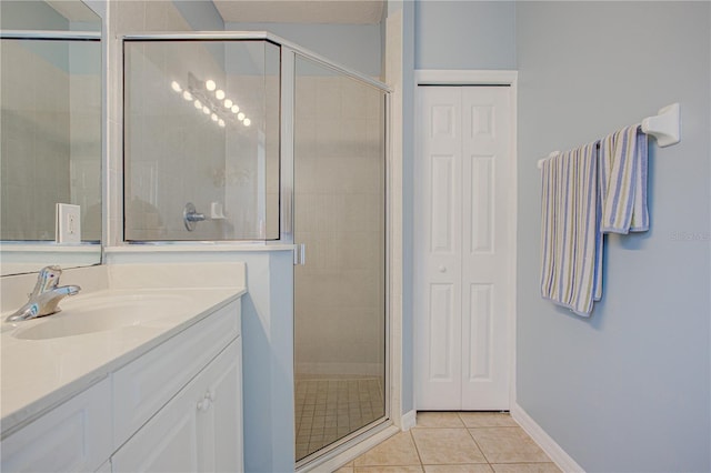 bathroom with tile patterned flooring, baseboards, a shower stall, and vanity