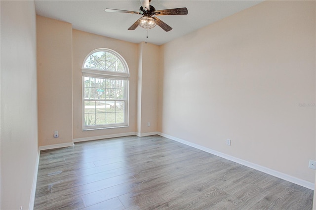 empty room with ceiling fan, wood finished floors, and baseboards