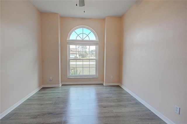 unfurnished room with a healthy amount of sunlight, ceiling fan, baseboards, and wood finished floors