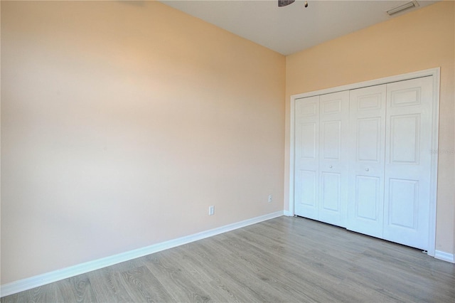 unfurnished bedroom featuring a closet, baseboards, visible vents, and light wood finished floors