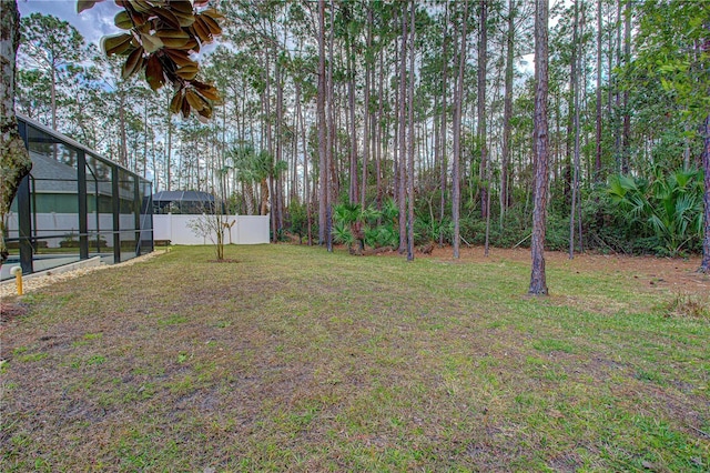 view of yard with glass enclosure and fence