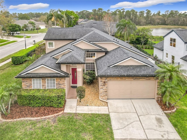 traditional home with stucco siding, a shingled roof, an attached garage, stone siding, and driveway