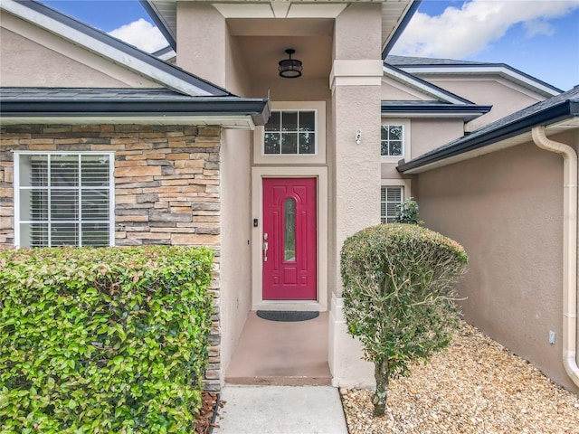 doorway to property with stone siding and stucco siding