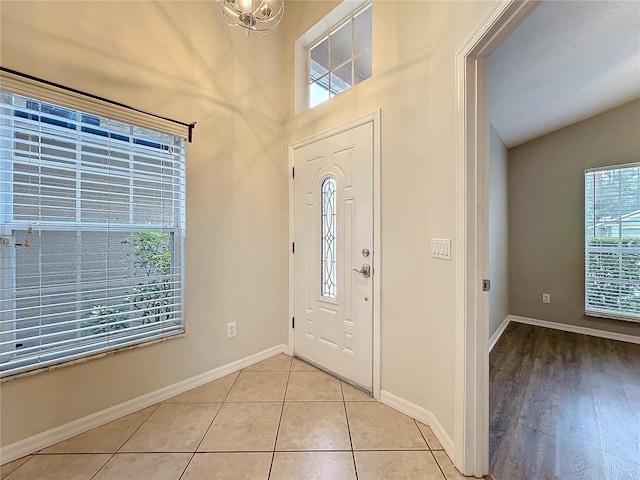 foyer entrance with vaulted ceiling, light tile patterned flooring, and baseboards