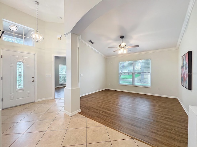 foyer entrance with ornamental molding, ceiling fan with notable chandelier, visible vents, and light tile patterned floors