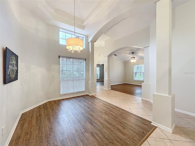 unfurnished room with arched walkways, light tile patterned floors, and baseboards