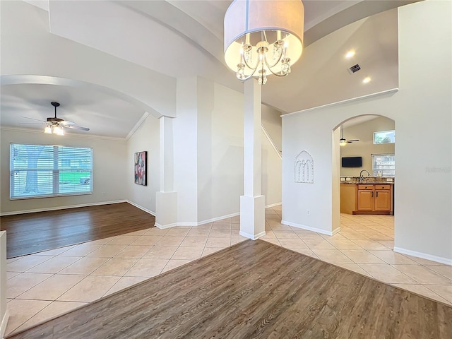 spare room featuring ceiling fan with notable chandelier, arched walkways, lofted ceiling, and light tile patterned floors