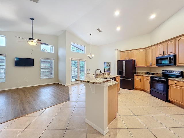 kitchen with light tile patterned floors, light stone counters, visible vents, black appliances, and a kitchen bar