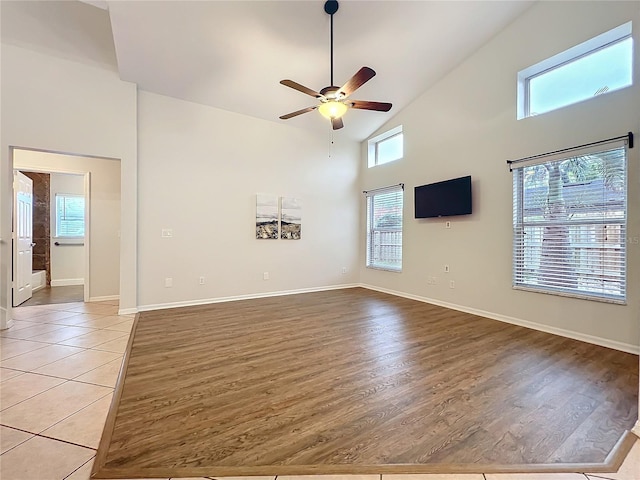 unfurnished living room featuring light wood-style flooring, high vaulted ceiling, and baseboards