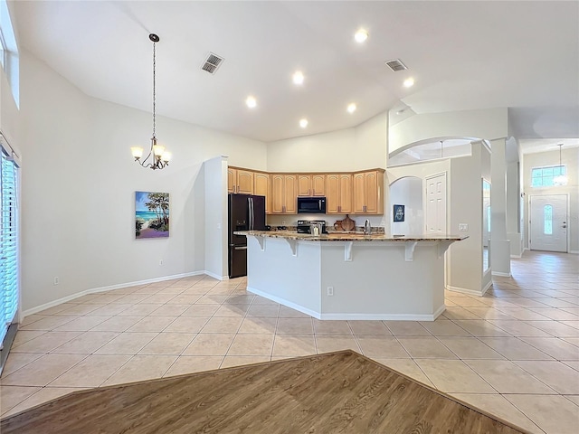 kitchen with a breakfast bar, light tile patterned flooring, visible vents, and black appliances