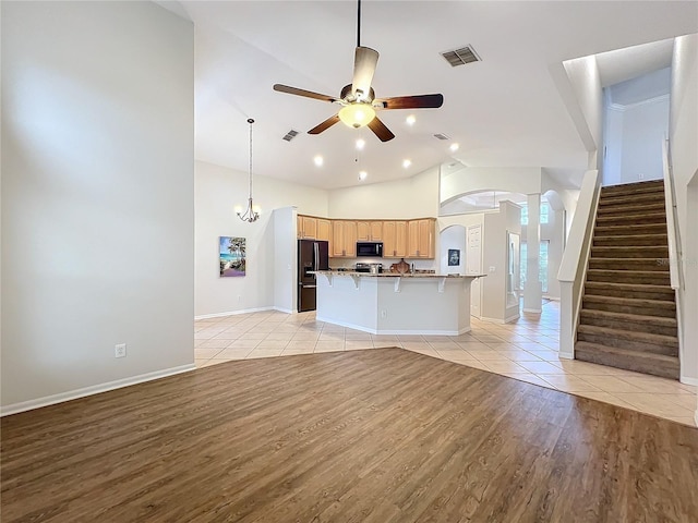 unfurnished living room featuring visible vents, a ceiling fan, light wood-type flooring, baseboards, and stairs