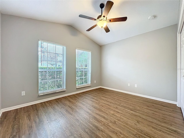 empty room with vaulted ceiling, ceiling fan, dark wood-type flooring, and baseboards