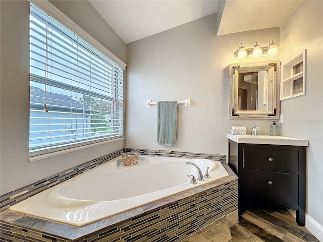 bathroom with a garden tub, wood finished floors, and vanity