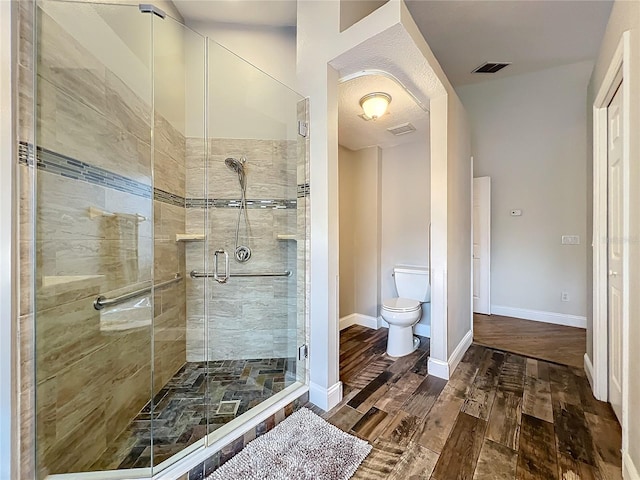 bathroom with visible vents, toilet, a shower stall, wood finished floors, and baseboards