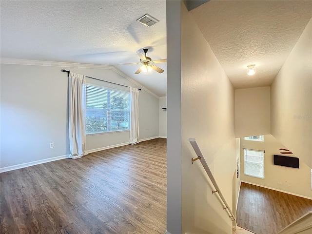 additional living space featuring baseboards, visible vents, wood finished floors, vaulted ceiling, and a textured ceiling