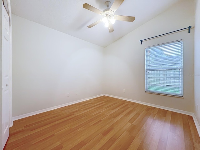 unfurnished room with lofted ceiling, light wood finished floors, a ceiling fan, and baseboards