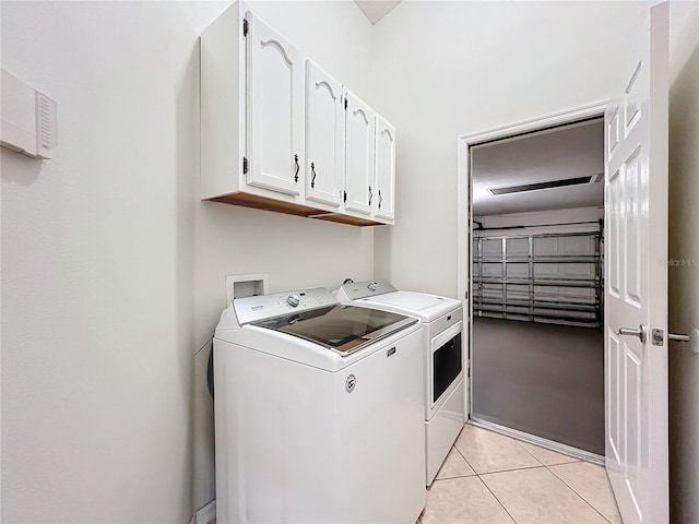 laundry room featuring a garage, cabinet space, light tile patterned flooring, and independent washer and dryer