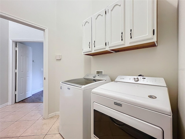 washroom with light tile patterned floors, independent washer and dryer, cabinet space, and baseboards