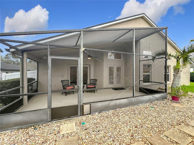 rear view of house featuring a lanai, a patio, and stucco siding