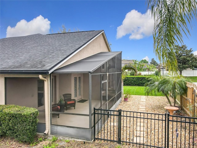 view of side of home featuring a shingled roof, a fenced backyard, a lanai, a patio area, and stucco siding