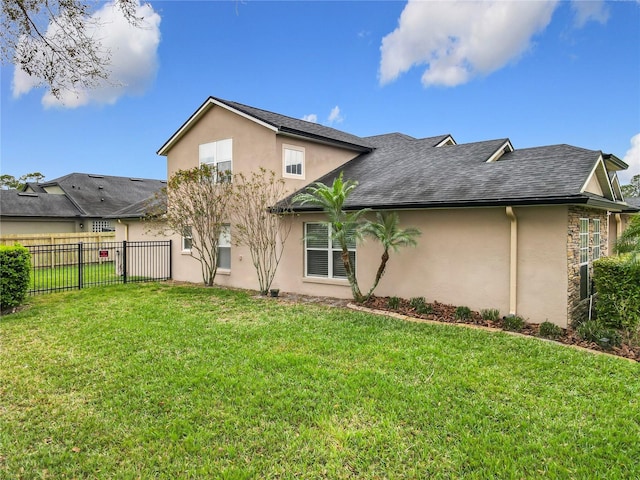 rear view of property with stucco siding, fence, a lawn, and roof with shingles