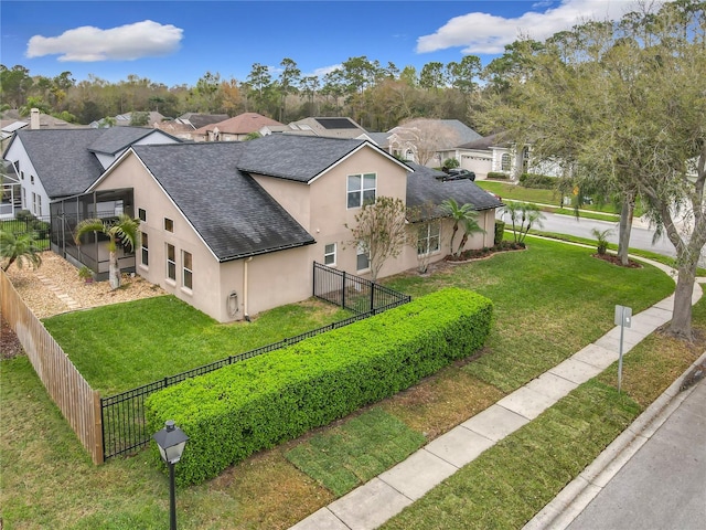 view of side of home featuring roof with shingles, stucco siding, a lawn, fence, and a residential view