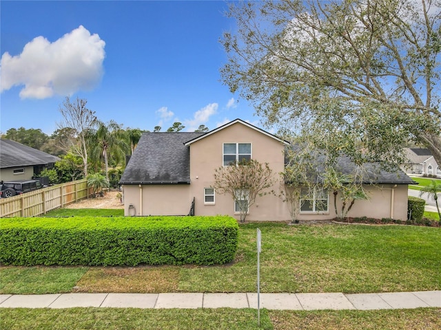 view of front of house with a shingled roof, fence, a front lawn, and stucco siding