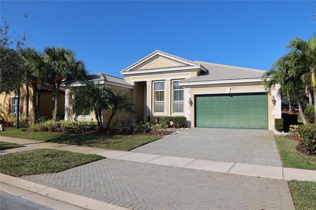 ranch-style house with decorative driveway, an attached garage, a tile roof, and stucco siding