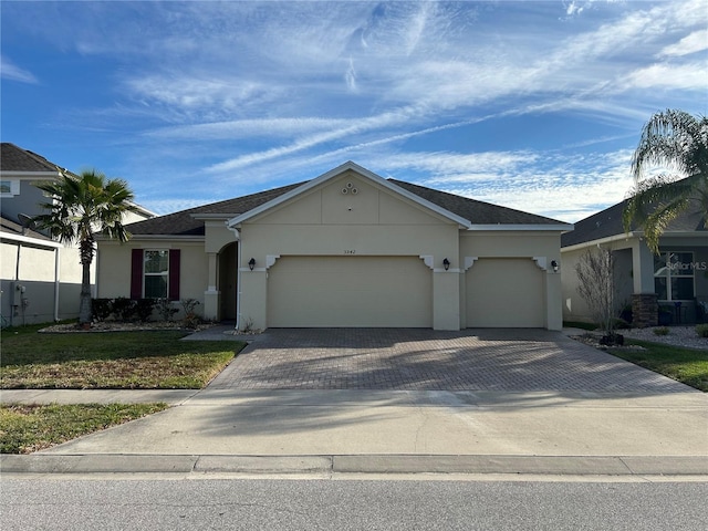 ranch-style house featuring a front lawn, decorative driveway, an attached garage, and stucco siding