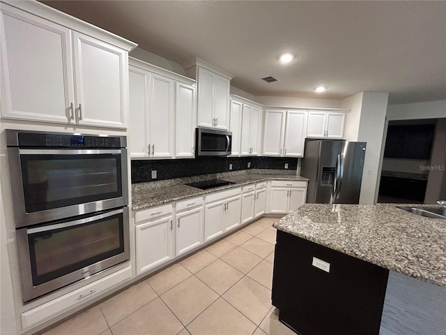 kitchen with tasteful backsplash, appliances with stainless steel finishes, white cabinets, and light tile patterned flooring