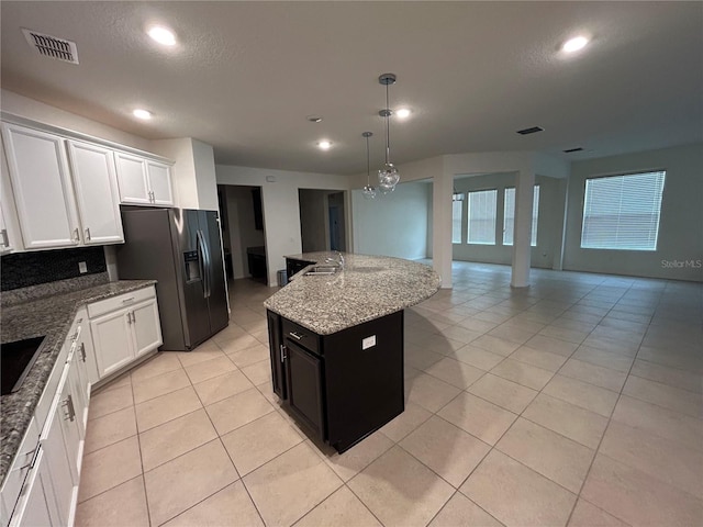 kitchen with pendant lighting, visible vents, black refrigerator with ice dispenser, open floor plan, and white cabinets
