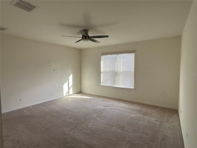 carpeted spare room with visible vents, ceiling fan, and baseboards