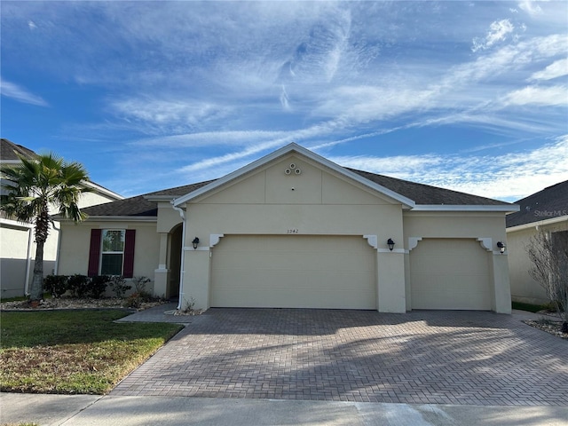 ranch-style house with an attached garage, decorative driveway, and stucco siding