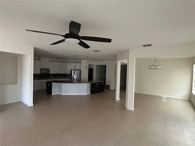 kitchen with stainless steel fridge, visible vents, dark countertops, open floor plan, and decorative light fixtures