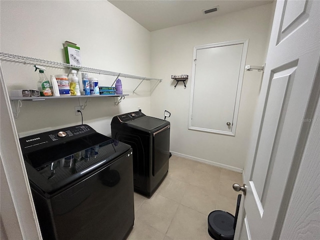 clothes washing area featuring laundry area, light tile patterned floors, visible vents, baseboards, and washing machine and dryer