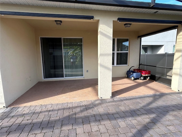 property entrance featuring a patio area, fence, and stucco siding