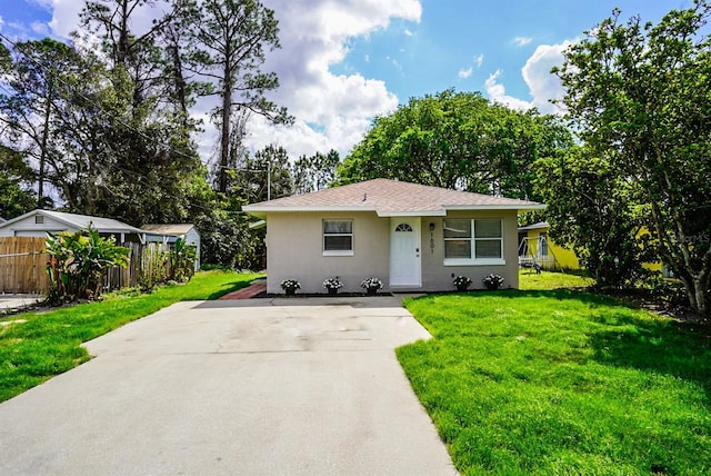 bungalow-style home featuring a shingled roof, a front yard, fence, and stucco siding