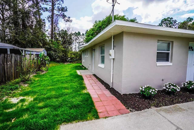 view of home's exterior with a yard, fence, and stucco siding