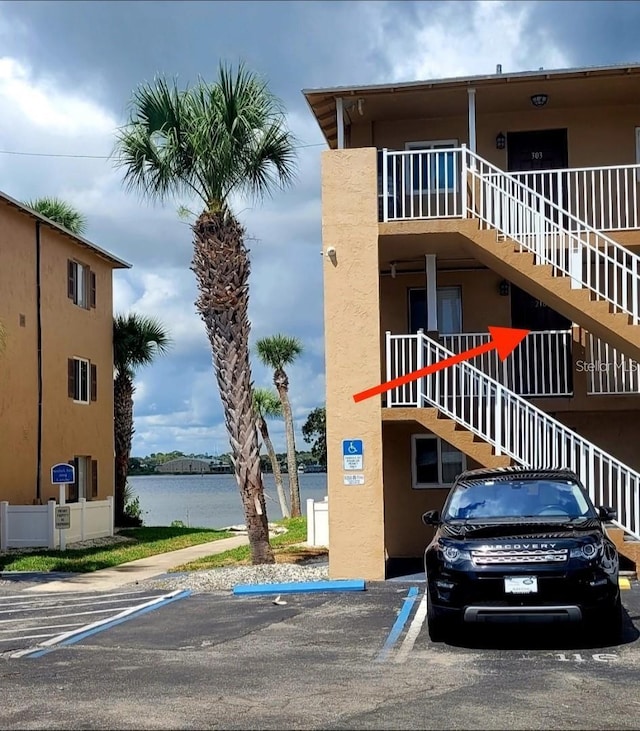 view of property with uncovered parking, a water view, and stairs