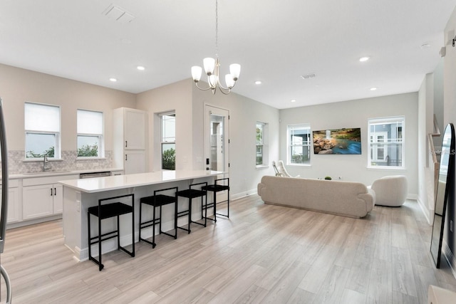 kitchen featuring light countertops, light wood-style flooring, white cabinetry, and a kitchen breakfast bar